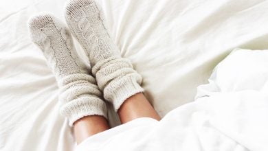 Woman's legs in bed wearing white wool socks