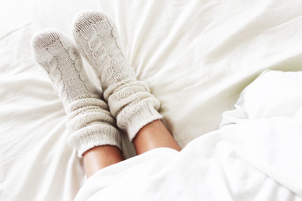 Woman's legs in bed wearing white wool socks