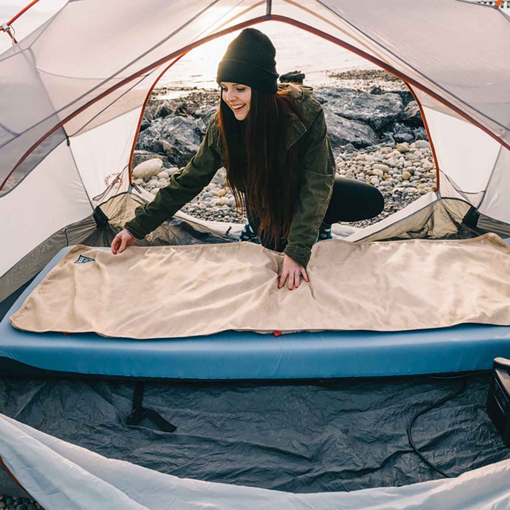 Designed to heat from the bottom up, it can be placed on top of camp mattresses, sleeping pads, or inside rooftop tents and RVs